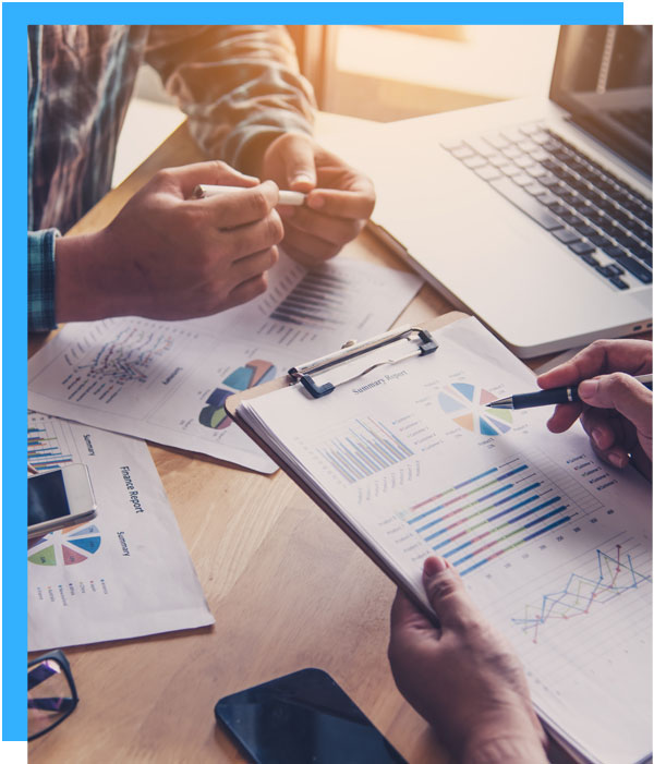Two individuals analyzing graphs and charts on papers in a business meeting.